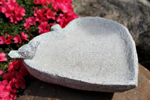 Granitvogelbad als Blatt mit einem Vogel auf dem Rand für den Garten