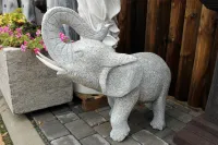 Elefant aus Granit mit weißen Stoßzähnen und Rüssel nach oben